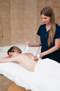 Woman receiving a relaxing body scrub treatment at a spa in Abu Dhabi, UAE.
